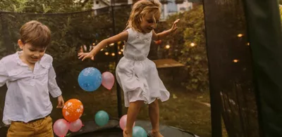 To barn hopper på en trampoline med ballonger. Foto