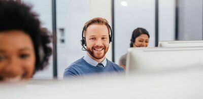 En mann sitter med headset i et kontorlandskap. Foto
