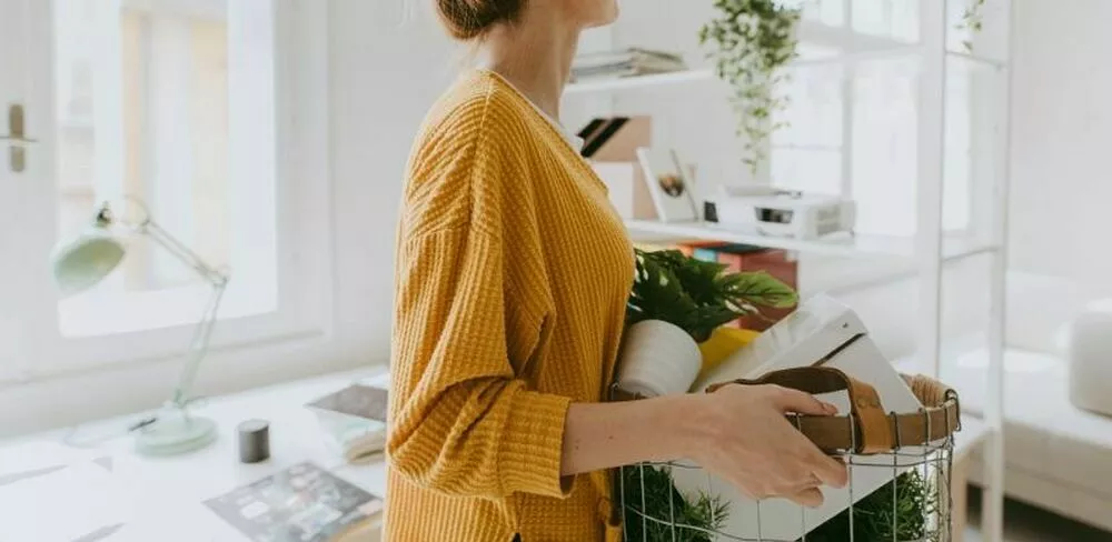 En dame med gul genser bærer en kurv. Foto