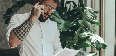 En mann snakker i telefonen og ser ned på et ark. Foto